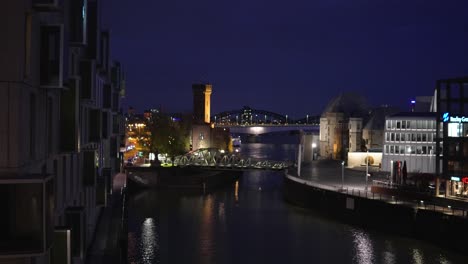 Witness-the-captivating-beauty-of-Cologne's-skyline-by-night,-as-the-city's-bridges-glow-with-a-warm-radiance,-inviting-exploration-and-adventure