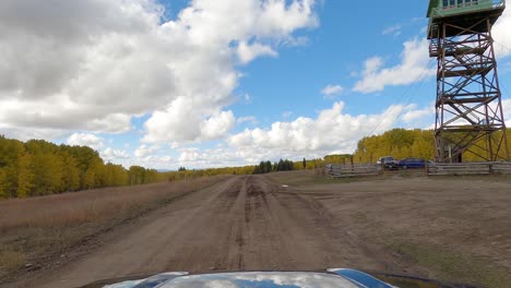 Passing-by-National-Forest-lookout-tower-surrounded-by-golden-woods,-car-POV-shot