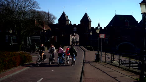 Multiple-Cyclist-passing-in-front-of-the-Historic-Land--and-watergate-the-Koppelpoort-in-Amersfoort