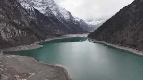 Drohnenflug-über-Den-Klöntalersee-In-Der-Schweiz---Hohe-Berge-Mit-Schnee-Im-Hintergrund