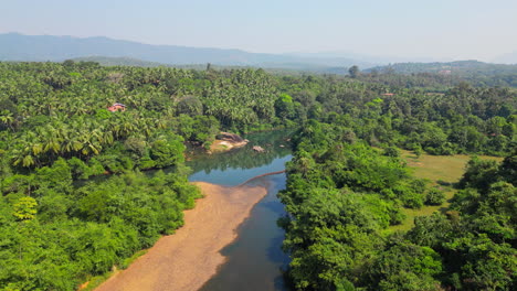Hermoso-Paisaje-Natural-De-Río-En-Medio-De-Un-Bosque-Verde-Tropical-Con-Montañas-En-El-Fondo-Goa-India-4k-Drone