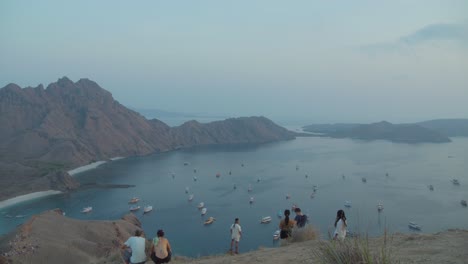 Tourists-On-The-Mountaintop-Overlooking-Sailboats-In-Padar,-Indonesia