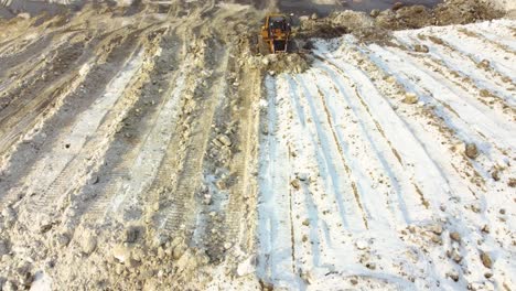 Aerial-View-Of-Bulldozer-Pushing-Snowy-Soil-After-Blizzard-In-Canada