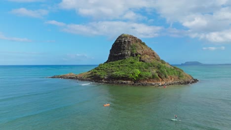 Aerial-Shot-of-Tourists-Kayaking-Towards-Mokoli'i-Island,-Also-Known-as-Chinaman's-Hat,-on-Sunny-Hawaiian-Day-on-Island-of-Oahu