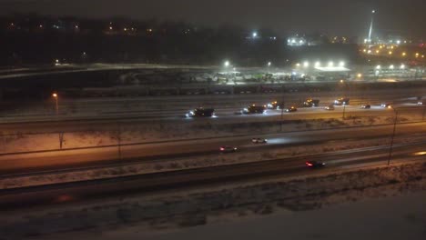 Vista-Nocturna-Invernal-De-Las-Concurridas-Carreteras-De-Montreal-Con-Nieve,-Luces-De-La-Ciudad-A-Distancia,-ángulo-Elevado