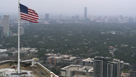 Drone-shot-that-reveals-American-flag-on-top-of-skyscraper-in-Houston,-Texas