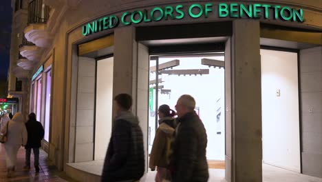 Fußgänger-Und-Käufer-Gehen-Nachts-Am-Geschäft-Der-Italienischen-Modemarke-United-Colors-Of-Benetton-Vorbei