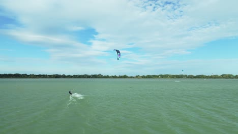 Eine-Luftaufnahme-Zeigt-Einen-Kitesurfer,-Der-An-Einem-Windigen-Spätsommertag-Schnell-Durch-Die-Gewässer-Der-Donau-Navigiert