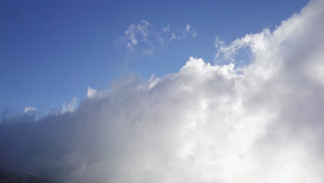 Weite-Sicht-Auf-Wolken,-Die-An-Einem-Sonnigen-Tag-über-Die-Hänge-Eines-Berges-Ziehen