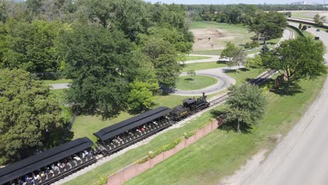 Old-steam-locomotive-train-carry-tourist-in-historic-Greenfield-village,-aerial-view