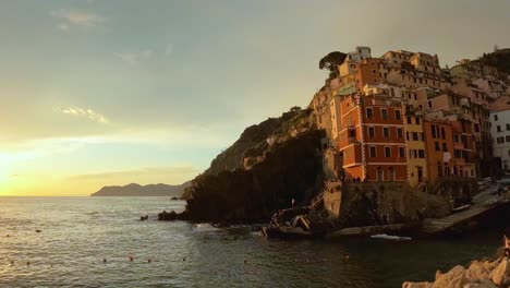 Sunset-time-lapse-over-Riomaggiore,-with-golden-light-silhouetting-the-village-against-a-vivid-sky-by-the-tranquil-sea
