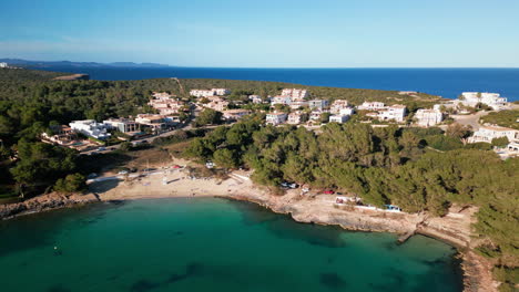 Serena-Bahía-De-Porto-Colom,-Mallorca,-Con-Aguas-Cristalinas-De-Color-Turquesa-Y-Casas-Costeras.