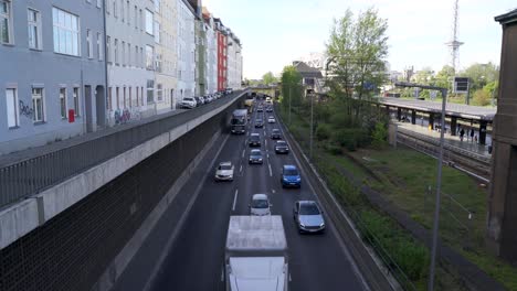 Statische-Kameraaufnahme-Einer-Großen-Straße-Mit-Einlaufendem-Verkehr-In-Berlin,-Neben-Der-Messe-Nord-ICC-Und-Einem-Bahnhof-Mit-Funkturm-Dahinter