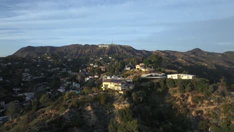 Vista-Aérea-De-Casas-De-Lujo-En-Las-Colinas-De-Hollywood,-El-Icónico-Cartel-De-Hollywood-En-Segundo-Plano.