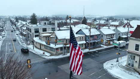 American-flag-waving-in-snow-covered-town-square-in-Palmyra,-Pennsylvania-during-winter