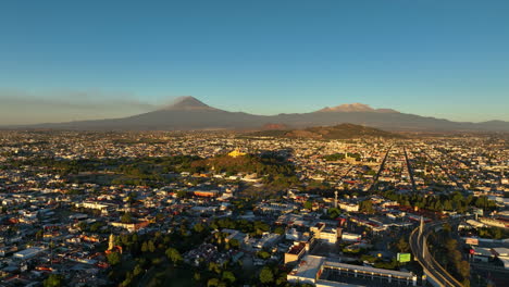 Drone-zooming-in-on-the-church-and-the-Cholula-pyramid,-golden-hour-in-Puebla,-Mexico