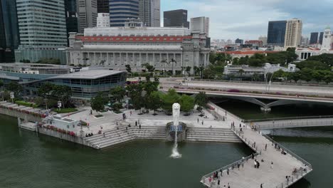 People-at-Merlion-Park-Promenade-with-CBD-Skyscrapers-in-Background,-Drone-Dolly-Out