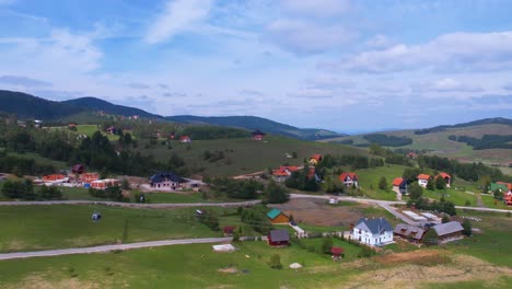 Aerial-View,-Landscape-of-Zlatibor-Mountain,-Serbia,-Gold-Gondola-Lift-Above-Village-and-Green-Fields