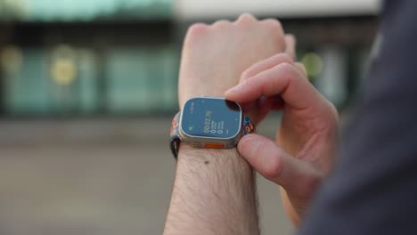 Caucasian-man-using-a-smartwatch-on-his-wrist,-starting-stopwatch-timer