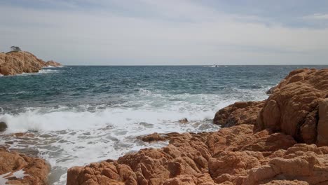 Panorama-Meereswellen-Brechen-Sich-An-Der-Mediterranen-Erdigen-Felsklippe-Im-Hintergrund-Der-Skyline-An-Der-Costa-Brava,-Einer-Küstenregion-Kataloniens