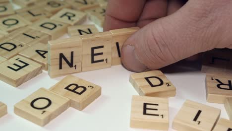 Man's-right-hand-forms-word-NEWS-from-Scrabble-letter-tiles-on-table