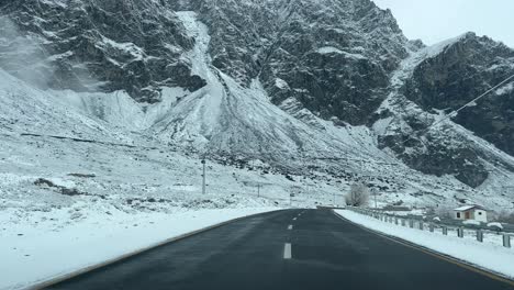 A-car-driving-on-Skardu-highway-during-snowfall,-Pakistan