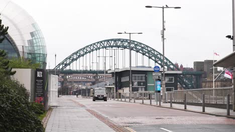 Taxi-Driving-On-Road-With-Tyne-Bridge-In-Background,-Newcastle