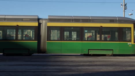 Modern-street-car-tram-passes-the-National-Theatre-building,-Helsinki