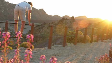 Young-man-climbing-over-guardrail-in-Teide-National-park,-dangerous