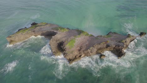 Aerial-reveal-morning-shot-of-Island-surrounded-by-water-waves