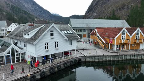 Torist-group-walk-along-dock-on-sightseeing-tour-at-early-spring,-rising-aerial-reveal