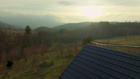 Una-Cabaña-Con-Vista-A-Un-Paisaje-Exuberante,-Con-árboles-Jóvenes-Que-Bordean-Un-Sendero-Descendente-Hacia-Un-Paisaje-Sereno-Y-Boscoso-Bajo-Un-Cielo-Suave-Y-Brillante