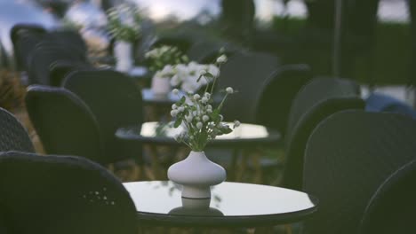 Glass-tables-outside-an-elegant-restaurant-with-small-floral-centerpieces