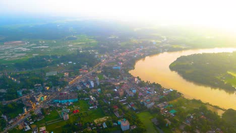 Aerial-suburban-village-by-Surma-river-in-Bangladesh,-early-morning-mist