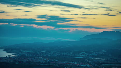 El-Cielo-Anaranjado-De-La-Hora-Dorada-Retrocede-Hasta-El-Resplandor-Del-Anochecer-Mientras-La-Ciudad-De-Málaga,-España,-Se-Ilumina-Por-La-Noche