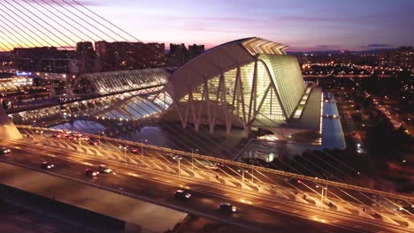 4K-Drone-view,-Evening-Sunset-Over-Valencia-Spain's-City-of-Arts-and-Sciences:-A-Cinematic-View,-traffic-driving-with-a-Family-Roller-Skating-Silhouette-under-bridge