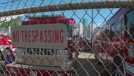 No-trespassing-sign-on-fence-of-yard-full-of-disabled-fire-trucks-with-downtown-Houston-in-the-background