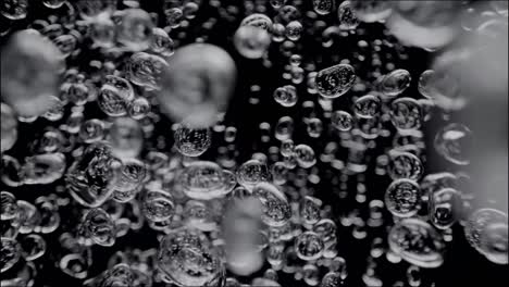 Ölige-Wasserblasen-Schweben-Isoliert-Vor-Einem-Schwarzen-Hintergrund-Und-Stellen-Eine-Faszinierende-Unterwassermischung-Dar.