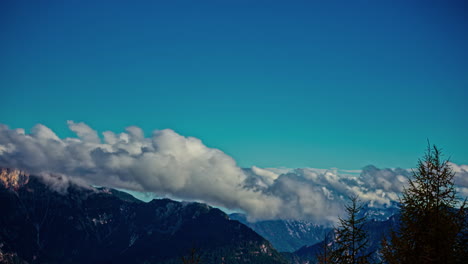 Starke-Weiße-Wolken-Rollen,-Während-Sie-über-Felsige-Berggipfel-Am-Himmel-Geweht-Werden