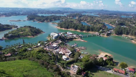 Aerial-View-of-Guatape-Lake,-Colombia,-Lakefront-Buildings-and-Picturesque-Landscape-Under-El-Penol,-Drone-Shot