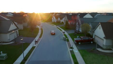 Red-car-driving-through-modern-housing-development-during-spring-sunset