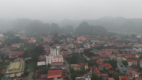 Aerial-Misty-Drone-Shot-of-Buildings,-House-Near-Hills-in-Ninh-Binh-Vietnam