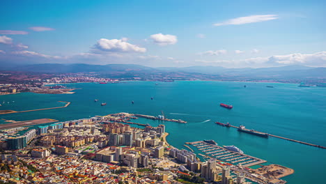 Zeitraffer-Der-Stadtlandschaft-Von-Gibraltar,-Während-Boote-In-Den-Hafen-Einlaufen-Und-Wolkenschatten-über-Gebäude-Ziehen