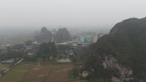 Aerial-Misty-Drone-Shot-of-Houses-and-Factories-Behind-The-Mountain