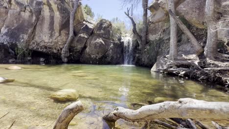 A-beautiful-waterfall-surrounded-by-trees,-branches-and-rocks