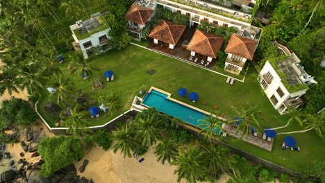 Aerial-view-tilting-away-from-a-woman-swimming-in-a-pool-at-resort,-in-Sri-Lanka