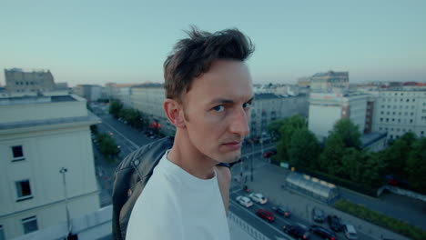 Young-man-on-city-rooftop-turns-toward-camera-with-serious-expression