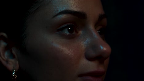 Woman-in-close-up-watching-a-screen-closely-as-the-light-changes-around-her-face