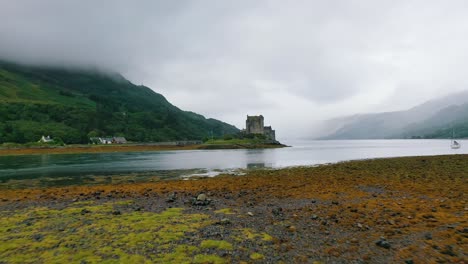 Low-aerial-shot-of-the-famous-Eilean-Donan-Castle-on-a-wet-and-cloudy-autumn-day-in-the-Scottish-Highlands,-Scotland,-United-Kingdom