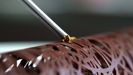 A-person-decorated-a-chocolate-with-a-gold-liquid,-close-up-shot,-insert-shot